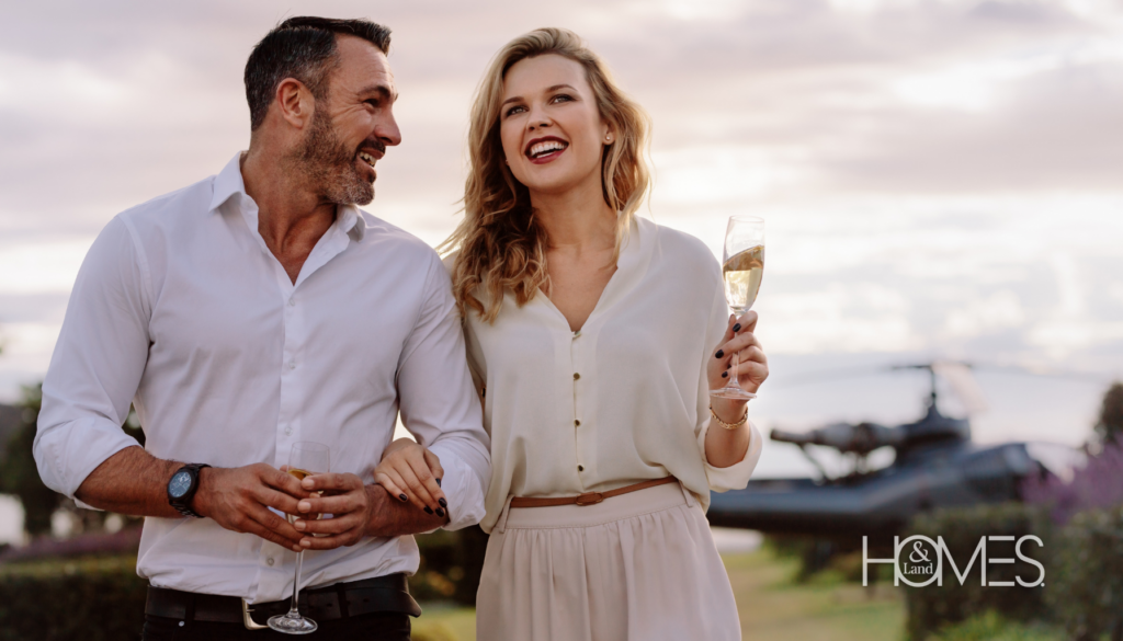 An elegant couple steps off a private helicopter, each holding a glass of champagne, ready to explore their luxurious new property. This striking image captures the sophistication and exclusivity of high-end real estate, symbolizing the successful results of a strategic marketing approach tailored to affluent clients.